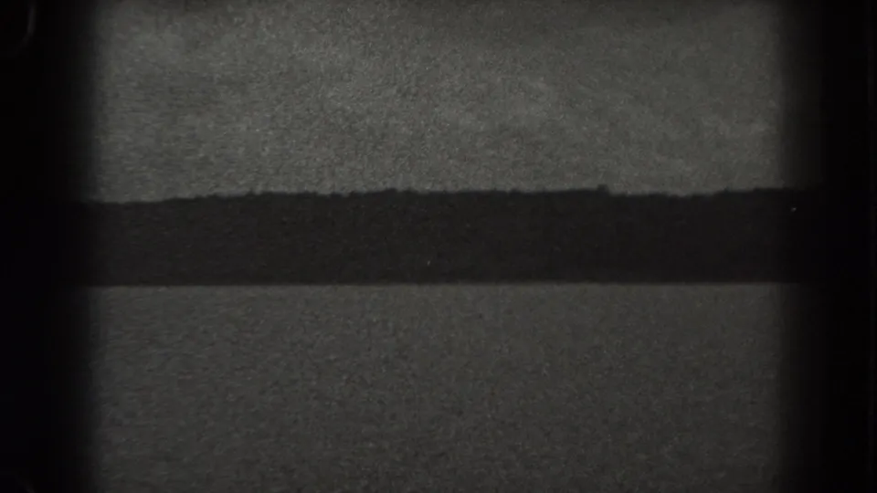 1938 New Jersey 8mm frame with open water, a low distant shoreline, cloudy sky, and dark gate edges.