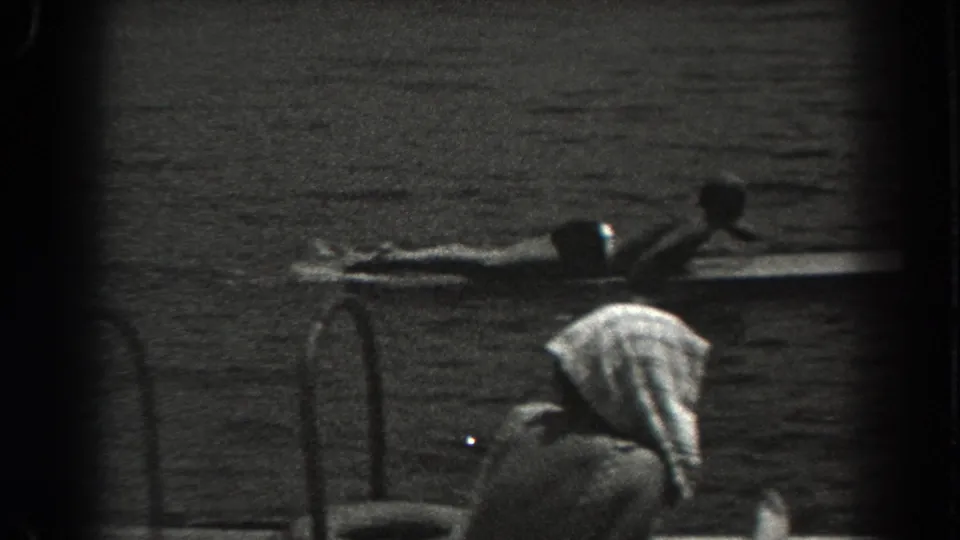 1938 New Jersey lake footage showing a person lying on a board and another towel-covered figure bending near the water.
