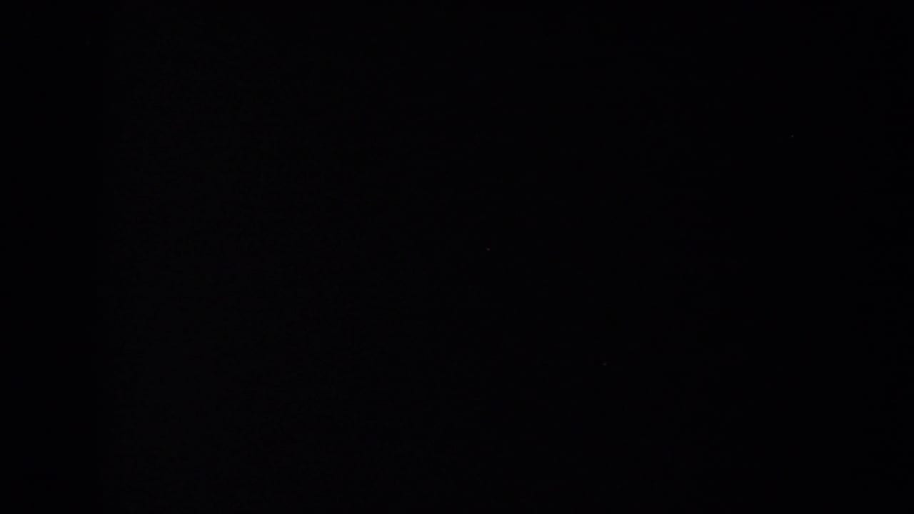 The 8mm frame is largely black, with only a faint border and trace of the prior lakeside pier scene visible at the edge.
