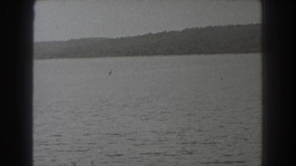 1938 New Jersey home-movie frame showing lake water, a far tree-lined shore, and heavy 8mm frame edges.