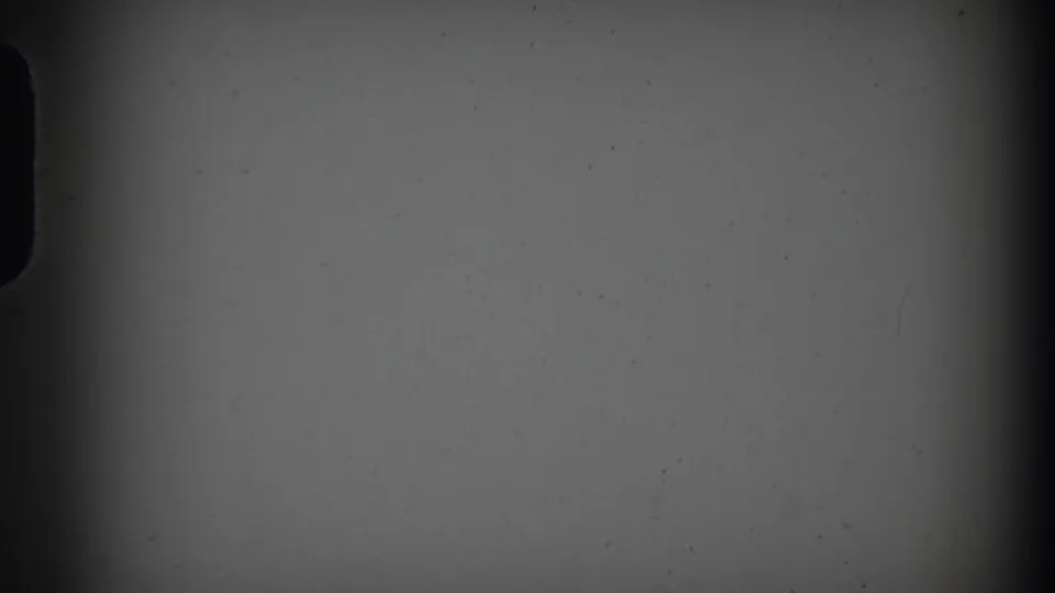 Black-and-white 8mm frame showing a blank or underexposed section with gate shadow, vignetting, and scattered dust.