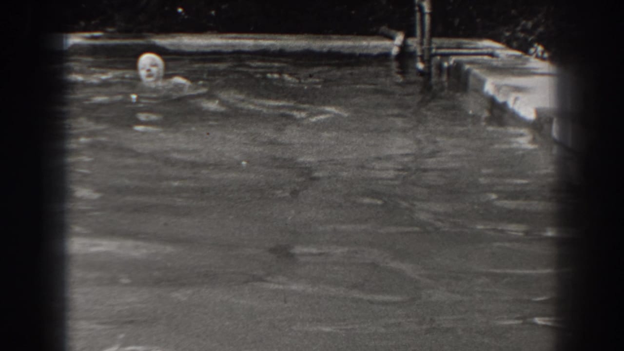 The swimmer’s capped head and shoulders are visible as she moves across a backyard pool in New Jersey home-movie footage.