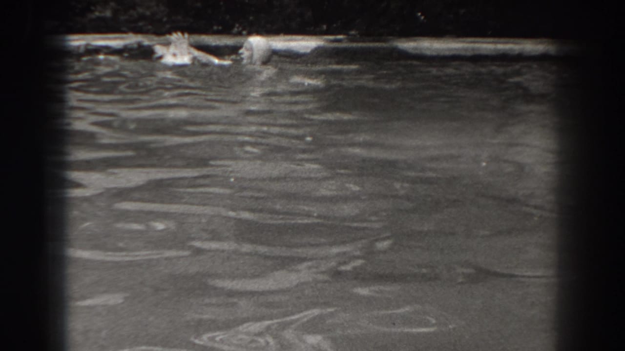 A woman in a swim cap appears at the surface of a New Jersey pond or lake in late-1930s home-movie footage.