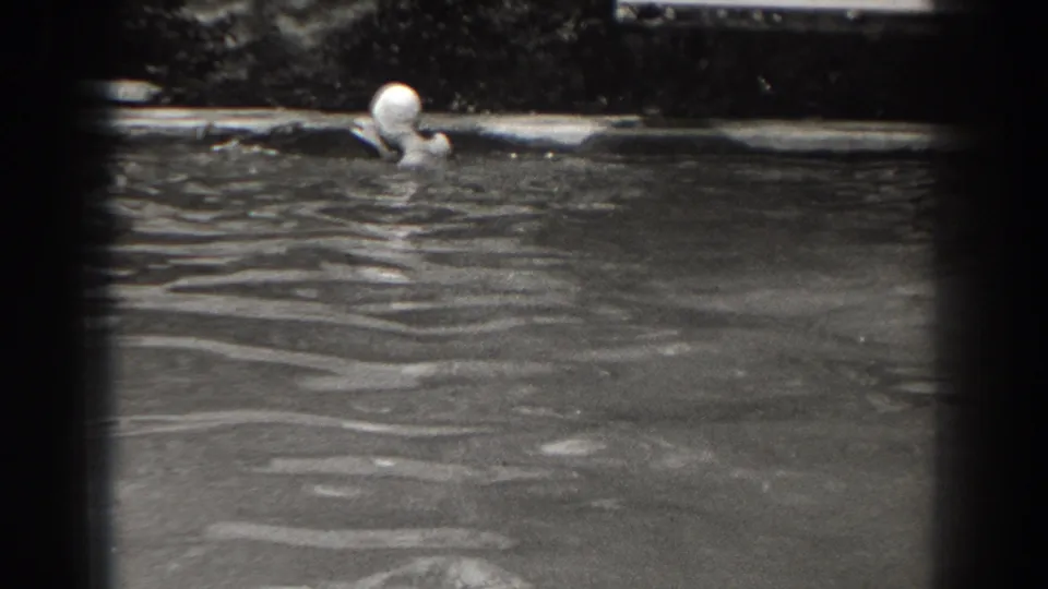 A swim-capped woman is visible from the shoulders up while moving through pond or lake water in 1938 New Jersey home-movie footage.