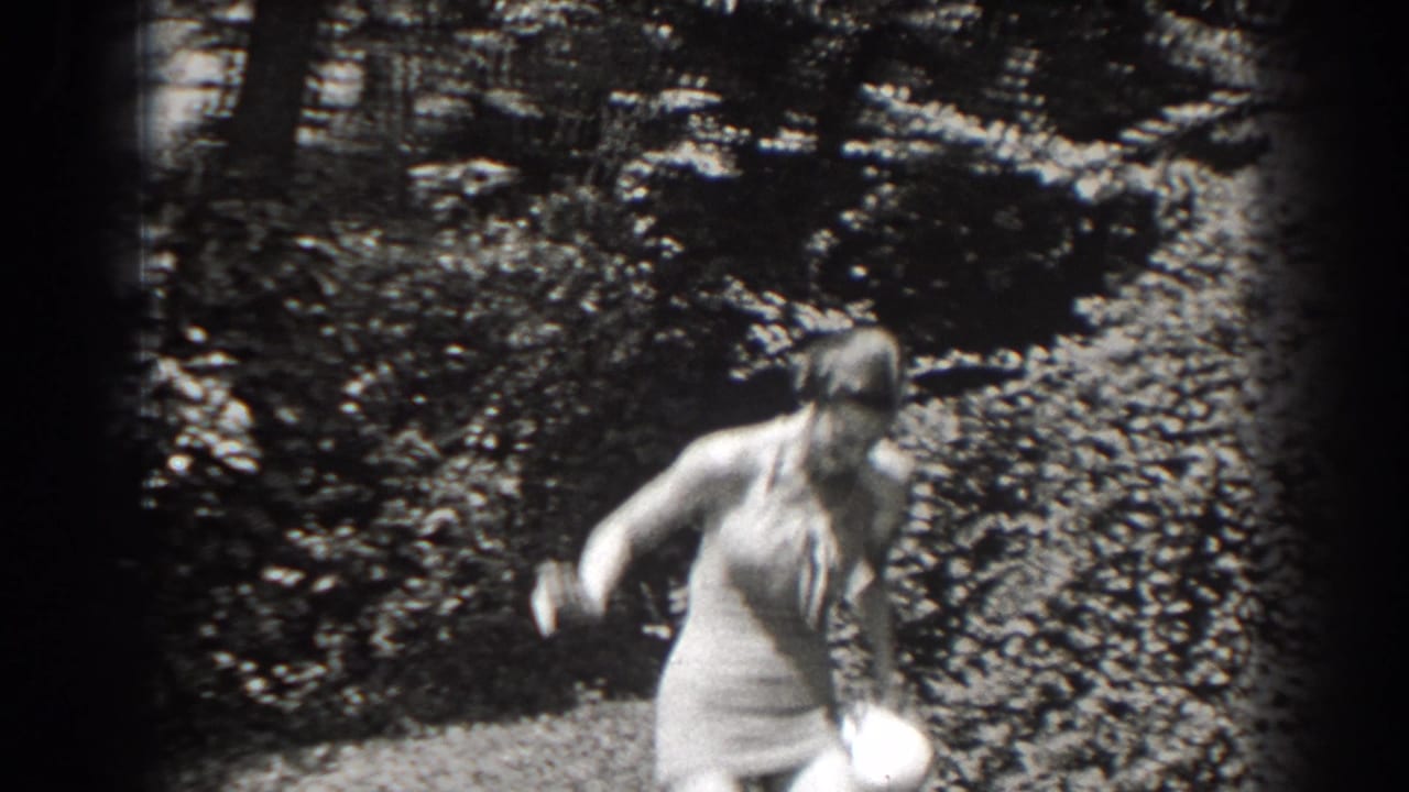 The woman shifts position in a wooded New Jersey setting, with her light swimsuit and hat visible against thick brush.