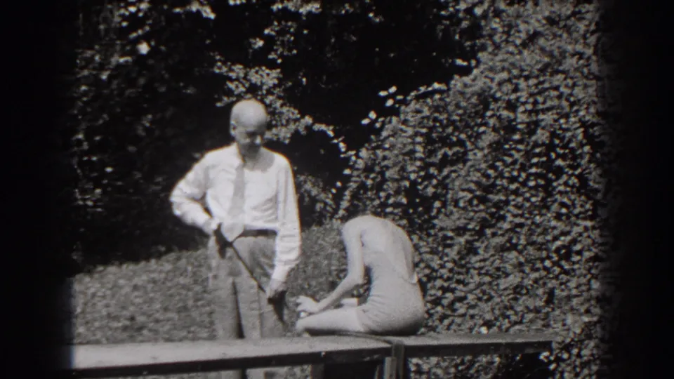 Near the end of the clip, the man looks downward while the young woman remains seated and bent over on the bench.
