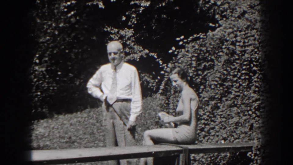 The final frame shows the man standing in a white shirt and tie as the woman sits on the bench in bright 1938 New Jersey garden light.