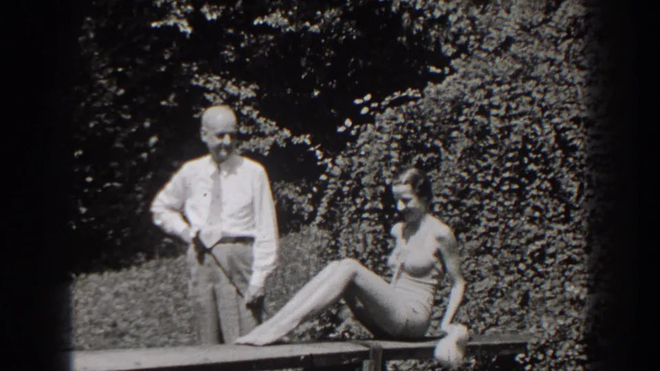 In the final frame, the woman extends her legs along the garden bench while the man stands beside her against the hedge.