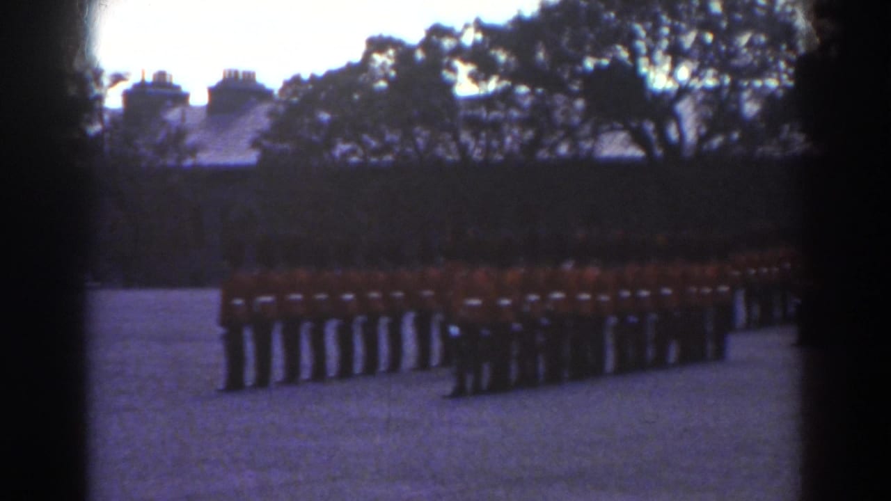 Rows of red-coated guards stand in ceremonial formation in a Quebec courtyard, with trees and rooflines behind them.