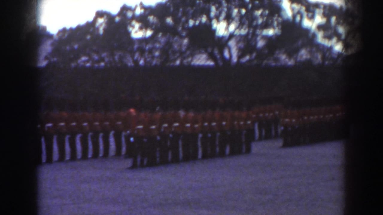 The 1938 Quebec home-movie view shows a broad guard formation in red tunics across a courtyard below dark trees.
