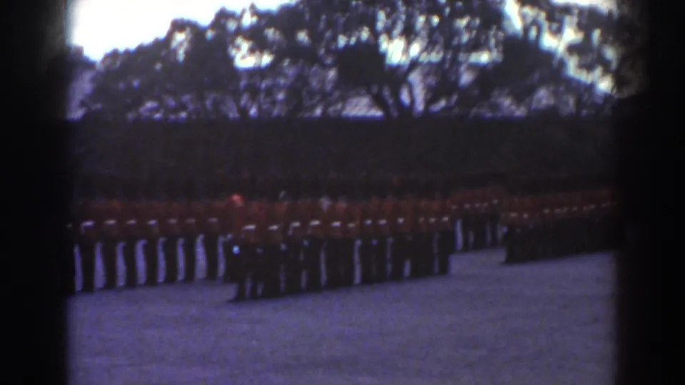 The 1938 Quebec home-movie view shows a broad guard formation in red tunics across a courtyard below dark trees.