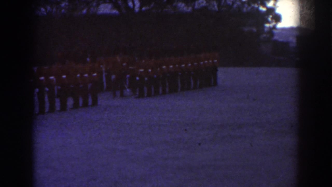 1938 Quebec frame showing red-coated soldiers in formation along the left side of a broad outdoor field.