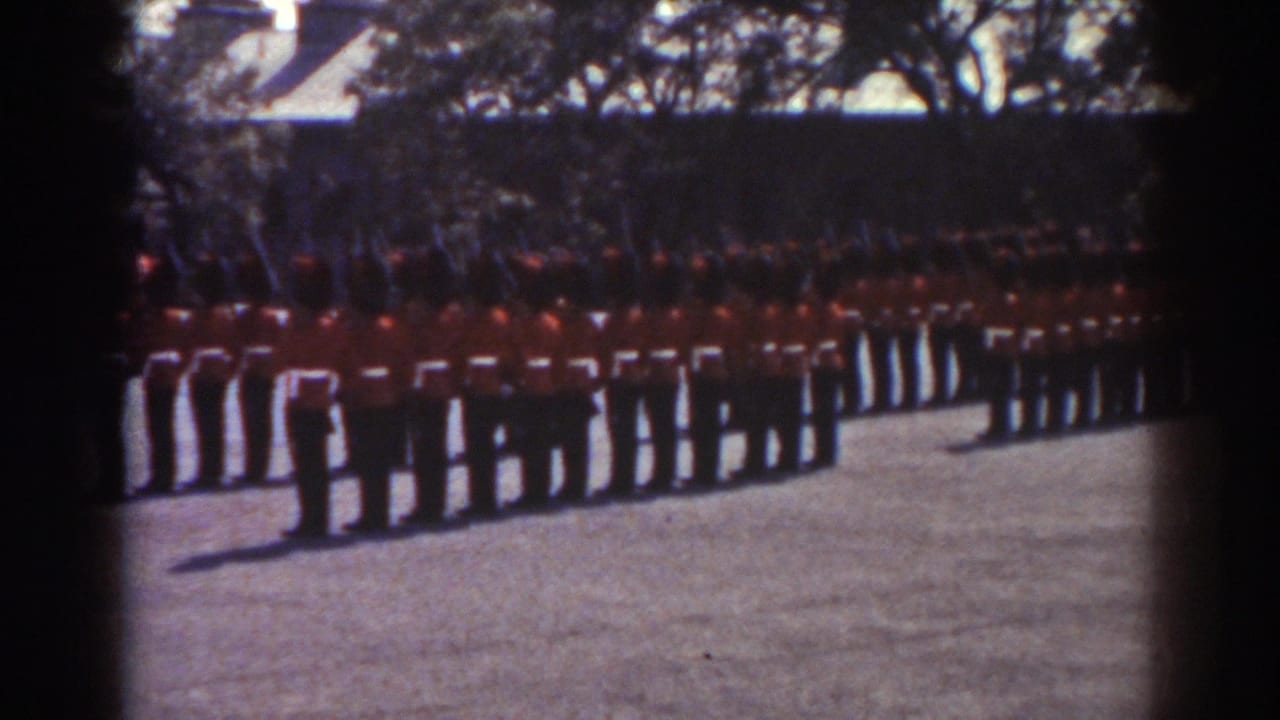 1938 Quebec footage frame with red-coated uniformed men aligned in drill formation, rifles visible across the row.