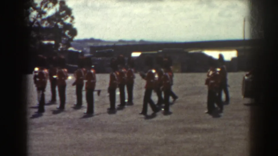 1938 Quebec frame showing guard band members halting and dispersing slightly on the gravel parade ground.
