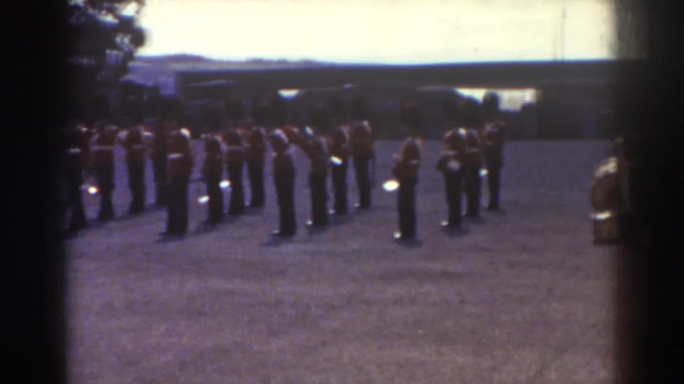 Uniformed marching band in Quebec, 1938, seen from a spectator viewpoint with brass instruments and dark hats visible.
