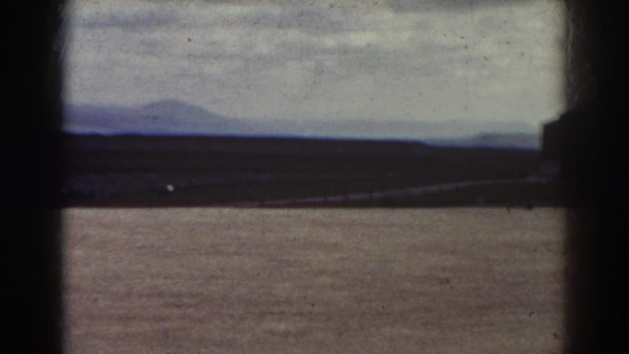 Flat open field with distant hills and a dark edge at the right side.