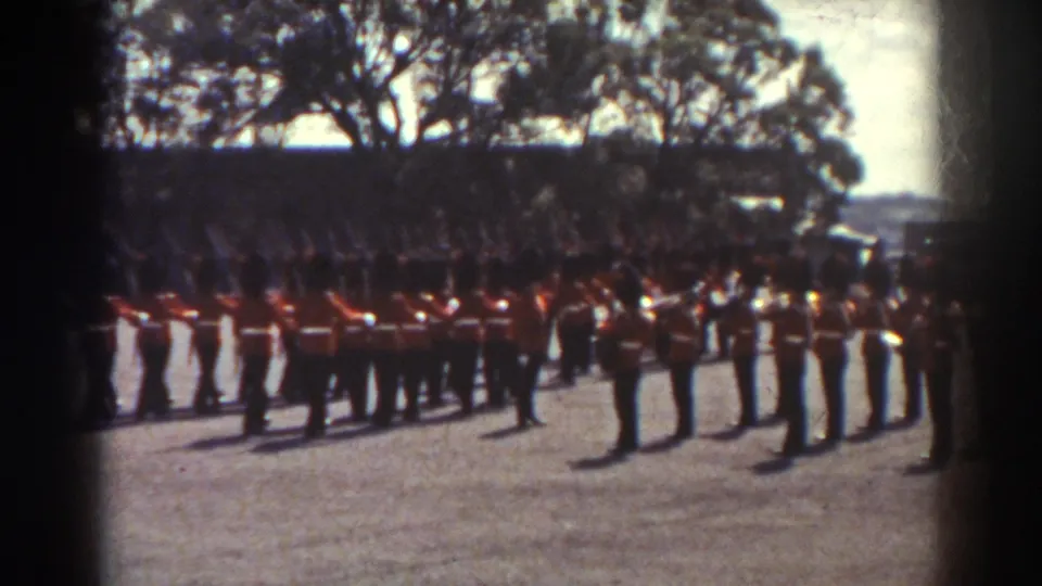 1938 Quebec parade view with red-coated soldiers in ranks and a foreground figure positioned before the formation.
