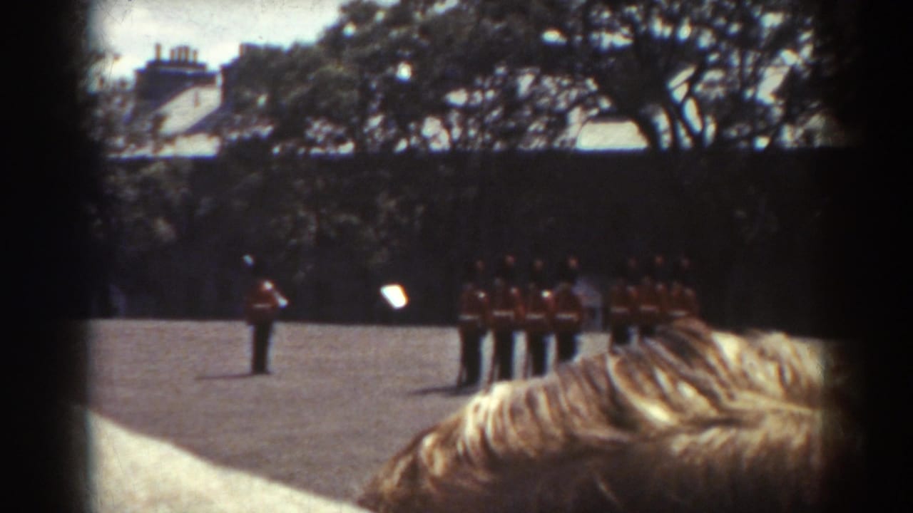 1938 Quebec home-movie frame showing red-uniformed soldiers in formal ranks, partly obscured by audience heads in the foreground.
