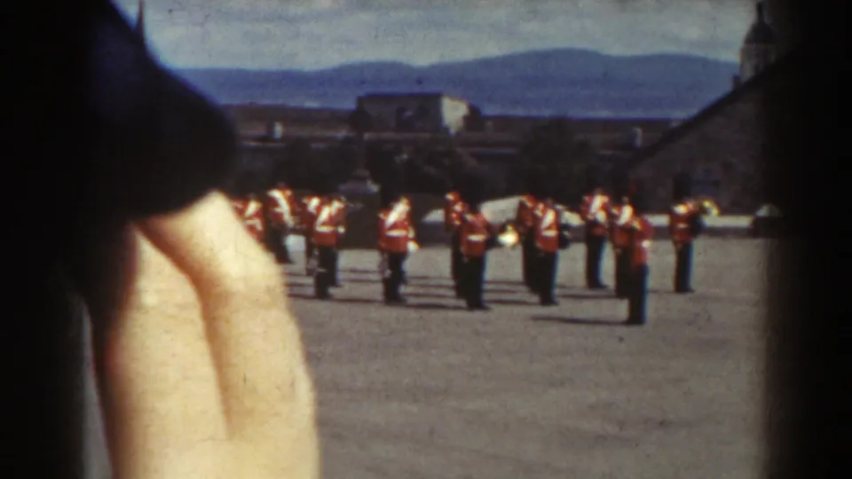1938 Quebec home-movie view of a ceremonial soldier line, with foreground spectators partially blocking the frame.