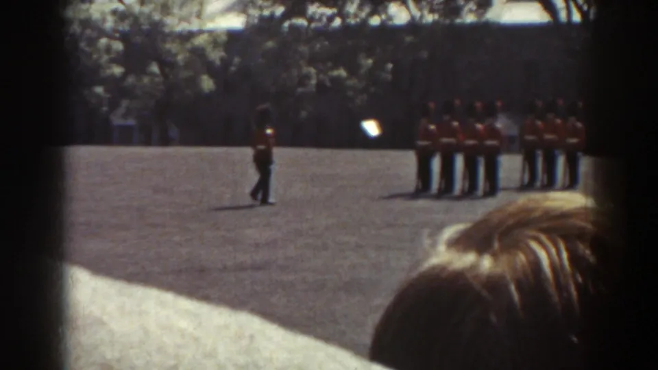 The 1938 Quebec frame shows a guard moving near a stationary formation, with a visitor's head partly blocking the lower foreground.