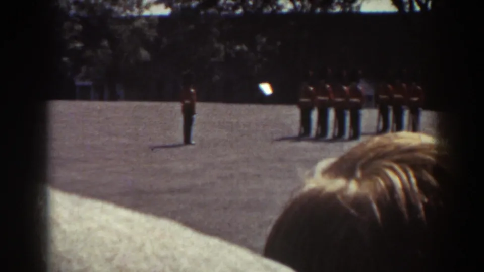 The final Quebec frame holds on the red-coated guard formation, with the light-haired spectator close to the camera at lower right.