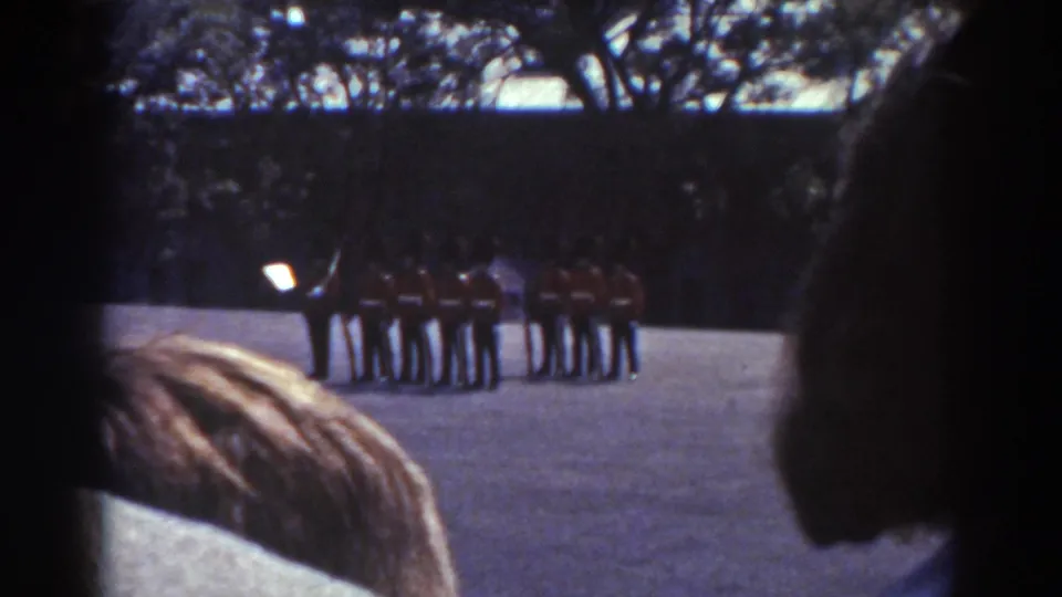 Final frame shows the red-uniformed group still assembled while nearby spectators partially frame the 1938 Quebec ceremony.