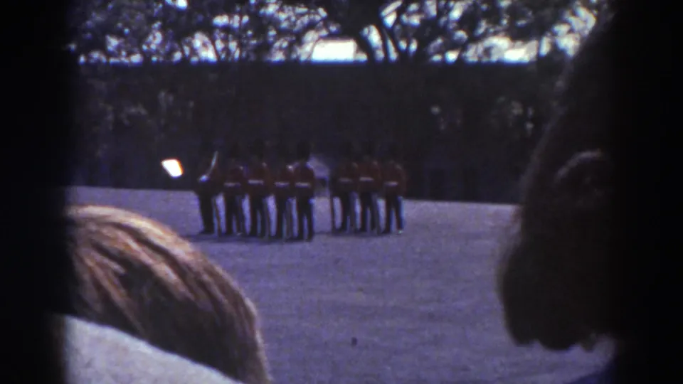 Quebec 1938 home-movie frame showing distant ceremonial guards in formation, partly obscured by spectators in the foreground.