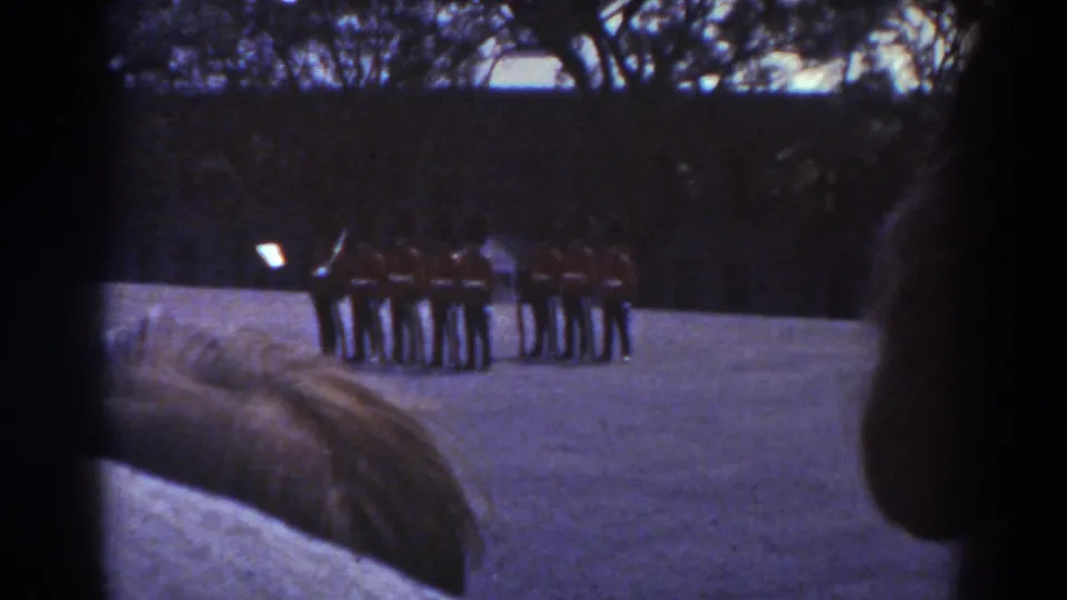 Quebec 1938 frame with a visitor-shot view of ceremonial guards, dark hedge and trees behind them, and spectators close to camera.