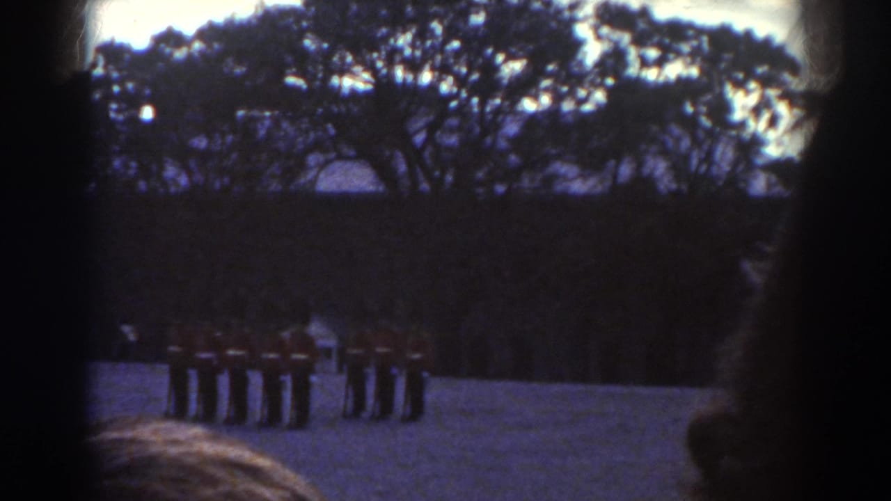 In Quebec 1938 home-movie footage, red-coated soldiers drill in an open area while onlookers partly frame the lower edge.