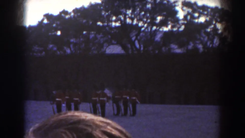 The 1938 Quebec home-movie view shows guards in red tunics and tall hats standing in a compact formation outdoors.