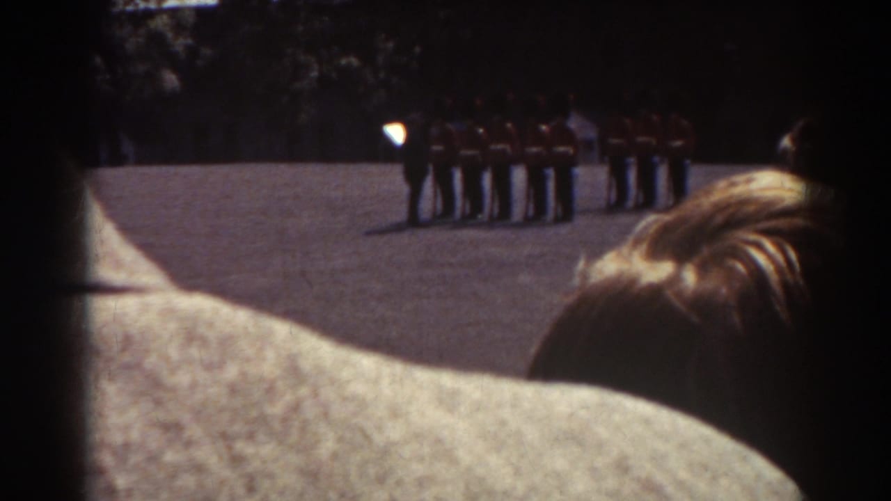 1938 Quebec home-movie frame showing soldiers lined up in the distance, partly blocked by spectators in the foreground.