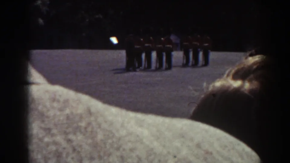 Home-movie frame from Quebec in 1938 with a distant soldier formation and spectators blocking the lower view.