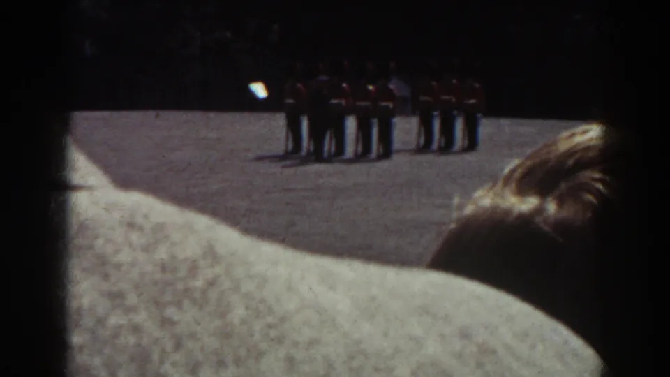In 1938 Quebec home-movie footage, foreground spectators partially block a distant group of uniformed soldiers on a sunlit field.