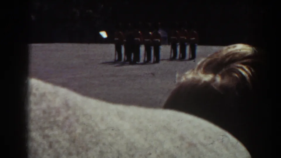 A spectator-view frame from Quebec shows uniformed soldiers in formation beyond the backs of nearby onlookers.