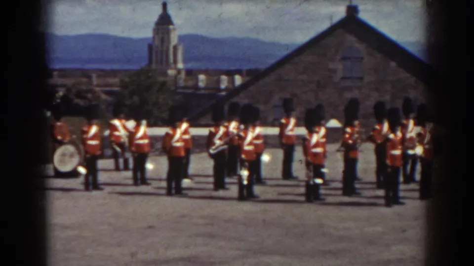 A wider 1938 Quebec view shows the red-uniformed band spread across the courtyard, with a bass drum, brass players, stone buildings, and hills beyond.