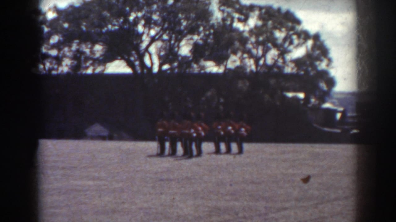 A small group in red uniforms remains lined up on the field near trees and a dark background.