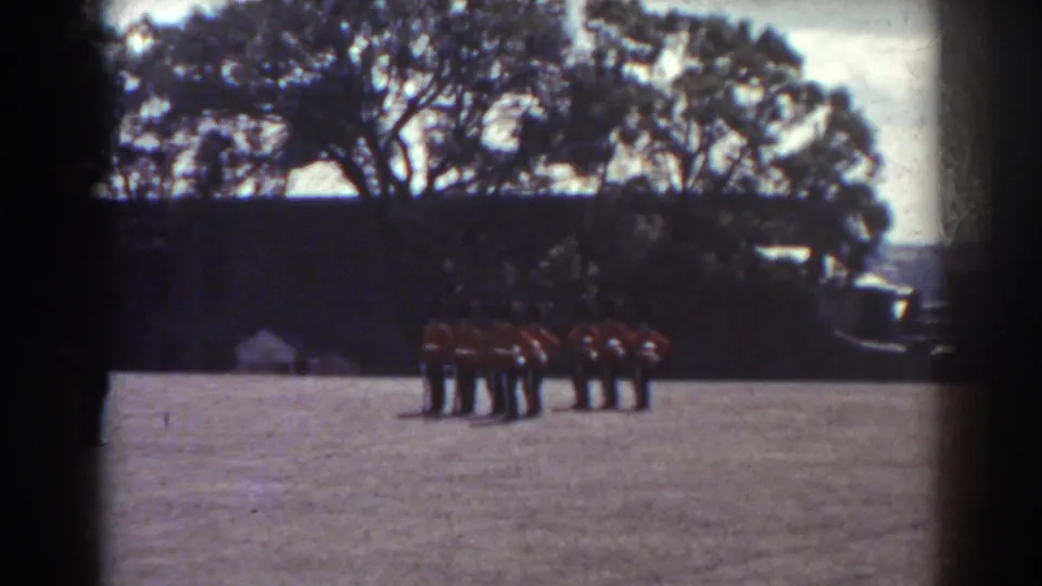 Soft 8mm frame from Quebec in 1938 showing a uniformed band cluster standing on an outdoor field.