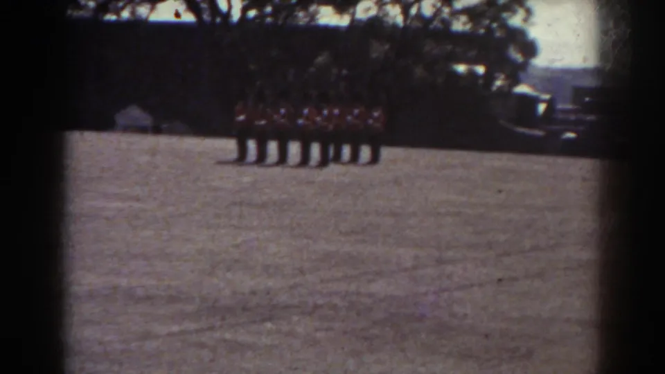 1938 Quebec home-movie frame with a line of uniformed people standing at attention on an open field.