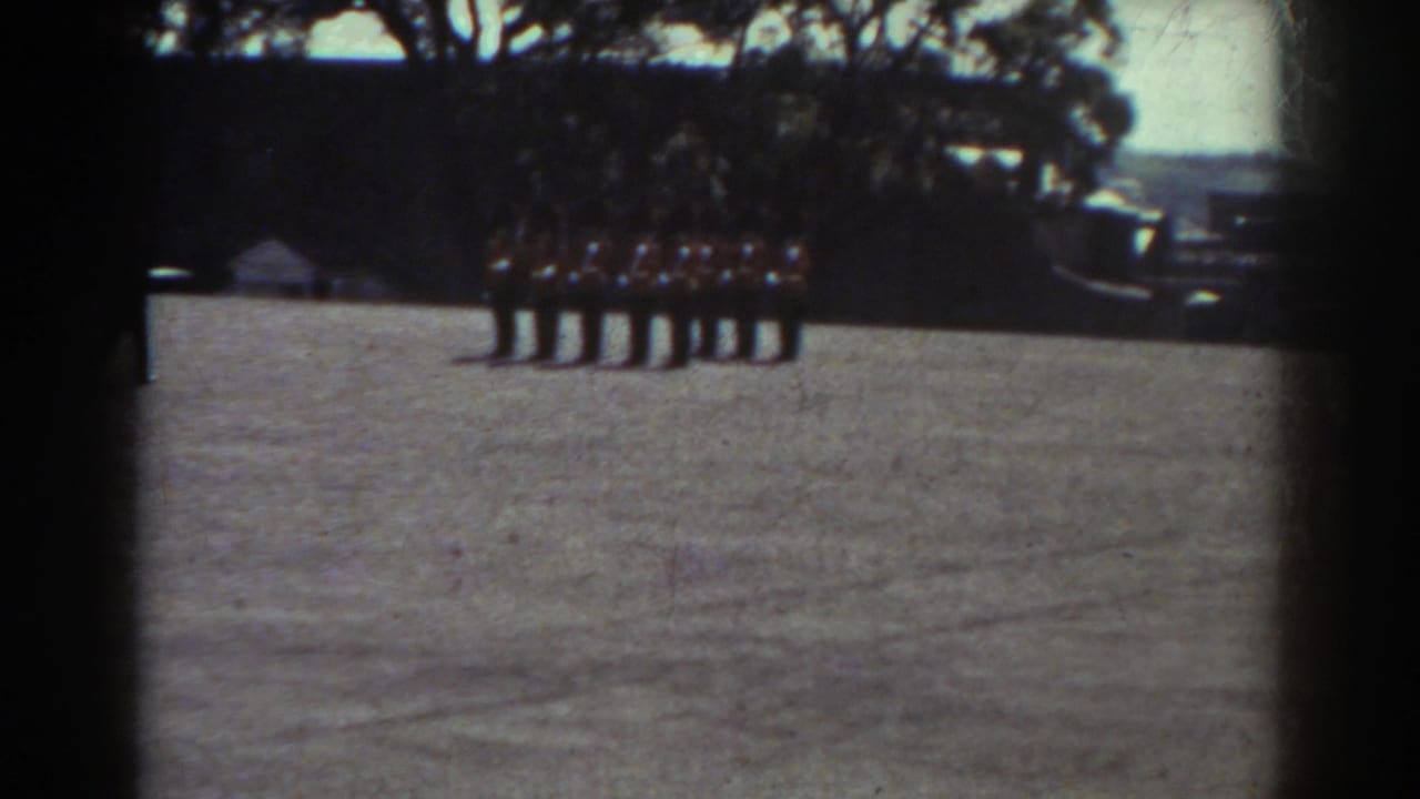 In Quebec 1938 home-movie footage, uniformed men stand at attention on a field with trees and possible vehicles in the background.
