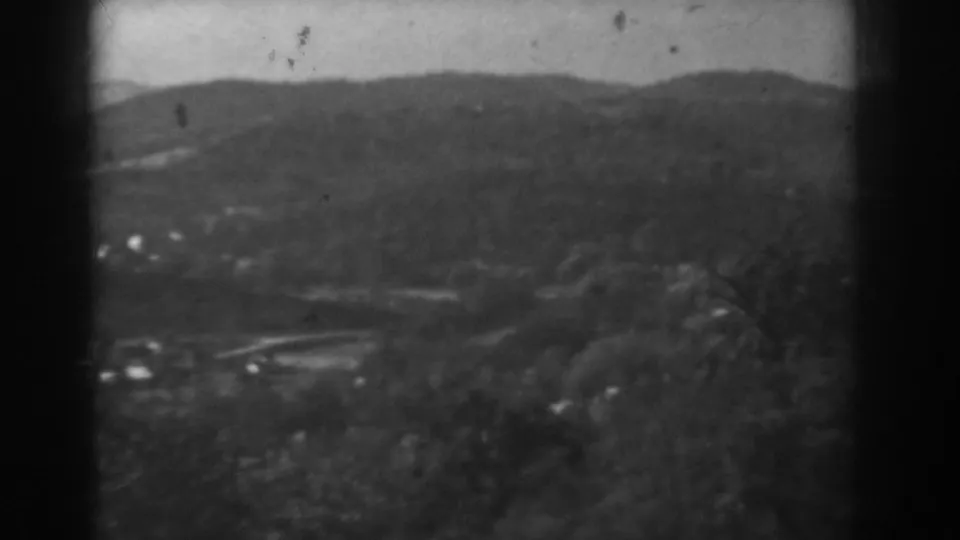 Final sampled frame from a 1938 8mm Vineland-area landscape view, showing hills, trees, distant homes, and foreground brush.