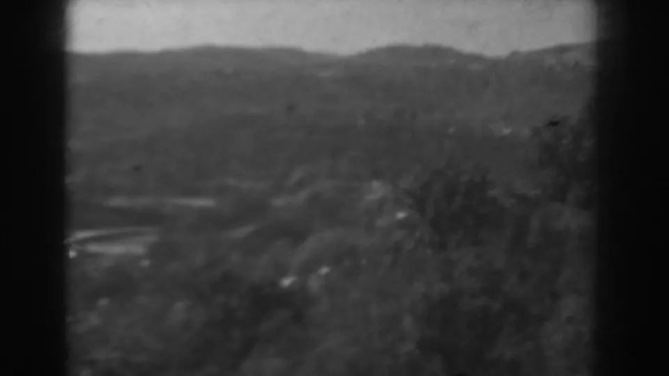 Soft black-and-white frame of rural hills and foreground trees in Vineland, New Jersey, from 1938 home-movie footage.