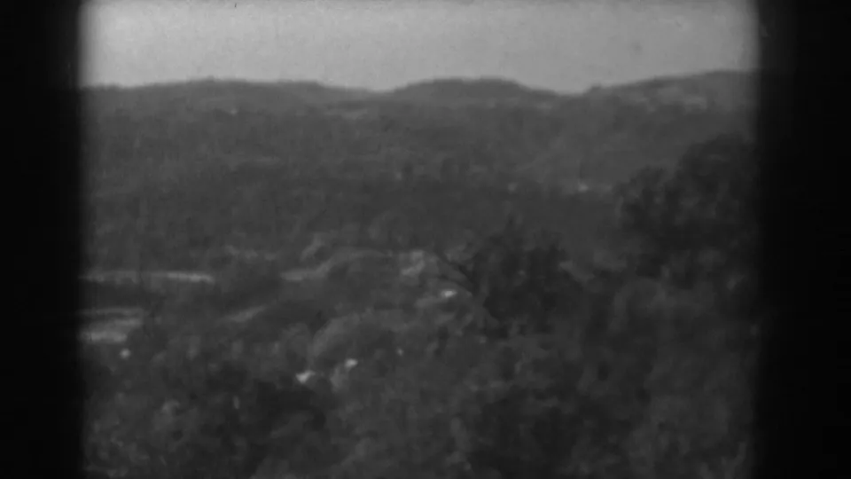 1938 8mm frame with tree-covered terrain, a distant ridge, and faint valley detail near Vineland, New Jersey.
