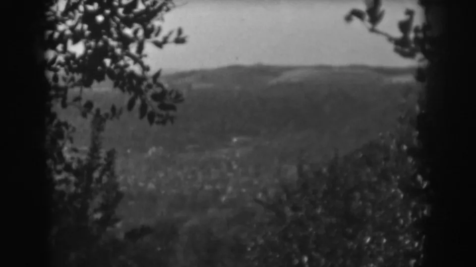Vintage 8mm frame from the Vineland, New Jersey clip showing a framed view of distant hills, valley, and foreground foliage.