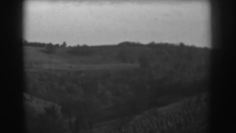 1938 Vineland, New Jersey home-movie frame showing open rural fields, low hills, and a distant tree line.