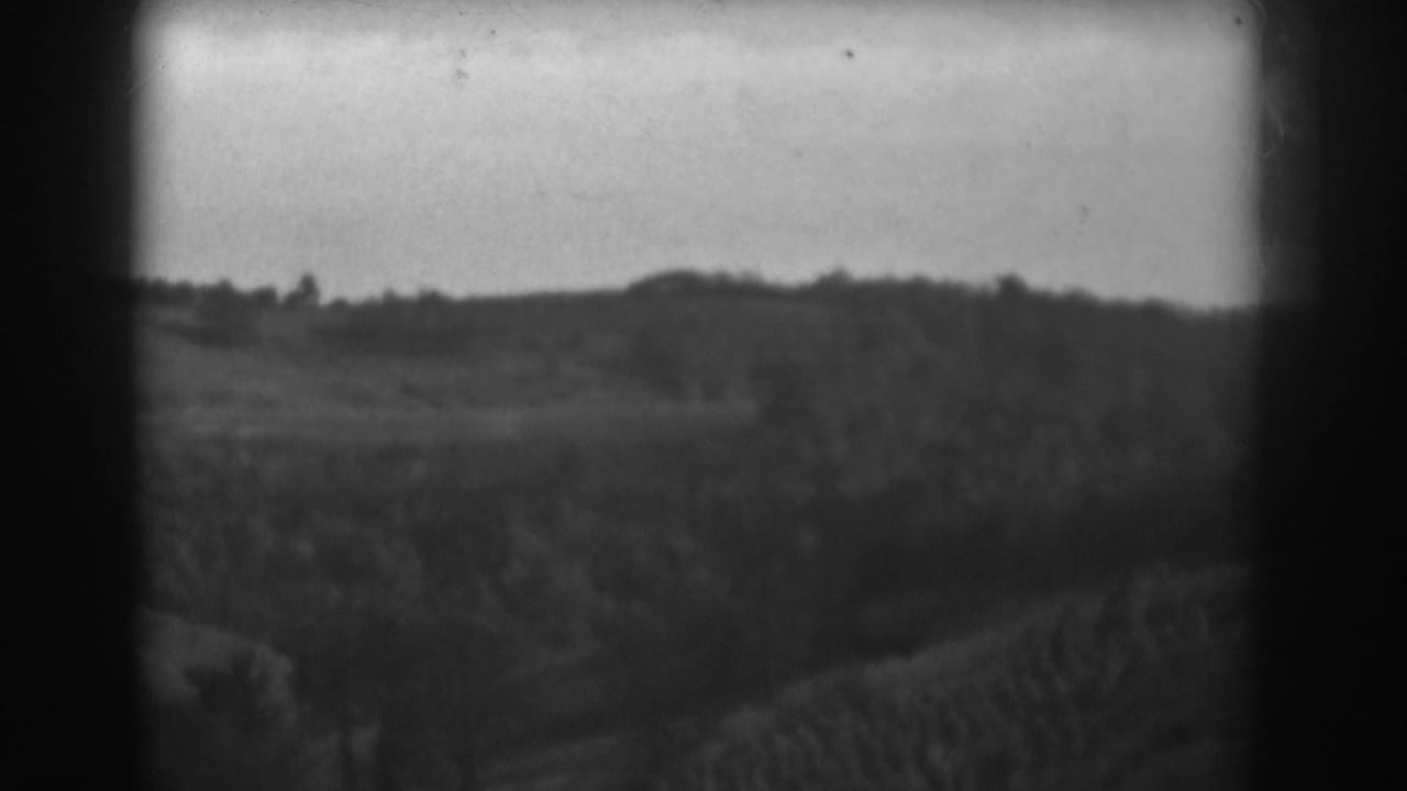Rural hillside and fields seen through dark 8mm frame edges.