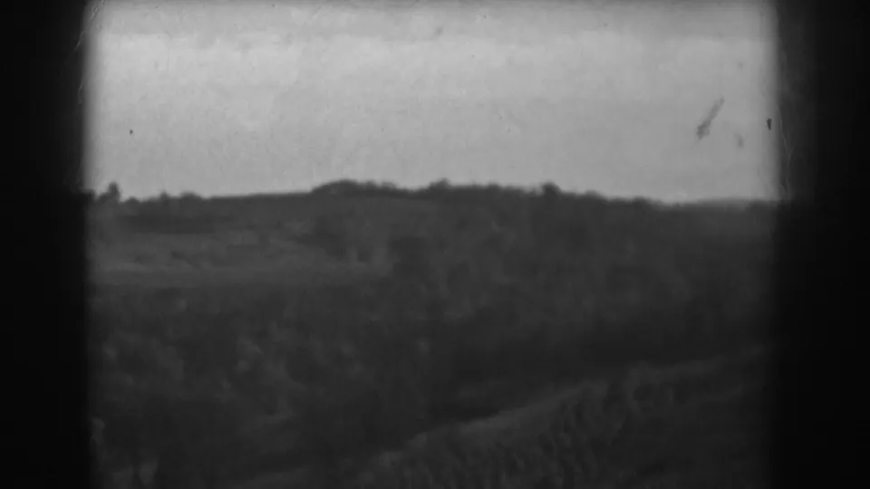 Vineland rural landscape with open fields, distant wooded ridge, and visible 8mm film grain.