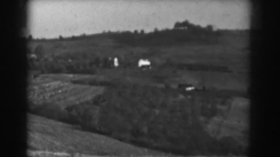 Vineland rural landscape in 1938, with fields, tree clusters, and small distant houses in soft 8mm focus.