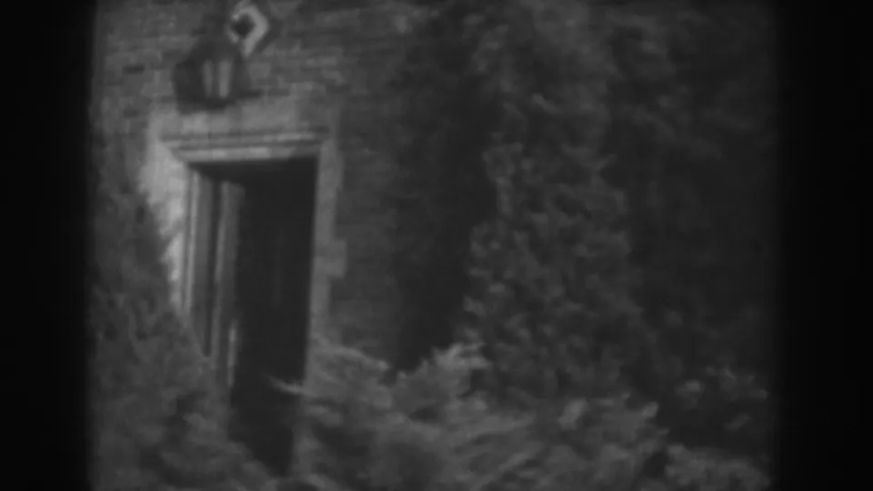 Vineland 1938 8mm frame showing a dark brick doorway surrounded by ivy, bushes, and overgrown vegetation.