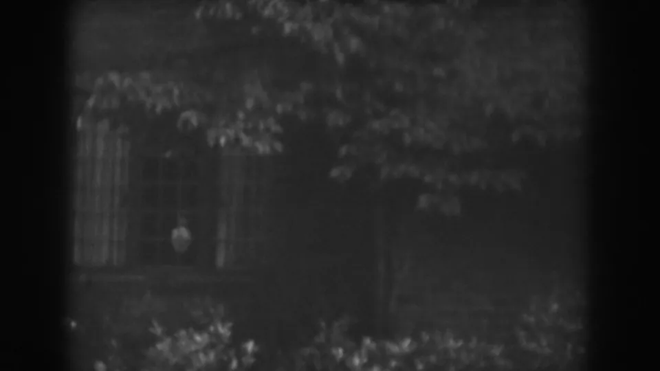 1938 Vineland, New Jersey 8mm frame showing the house window, surrounding leaves, and a faint person-like shape inside.