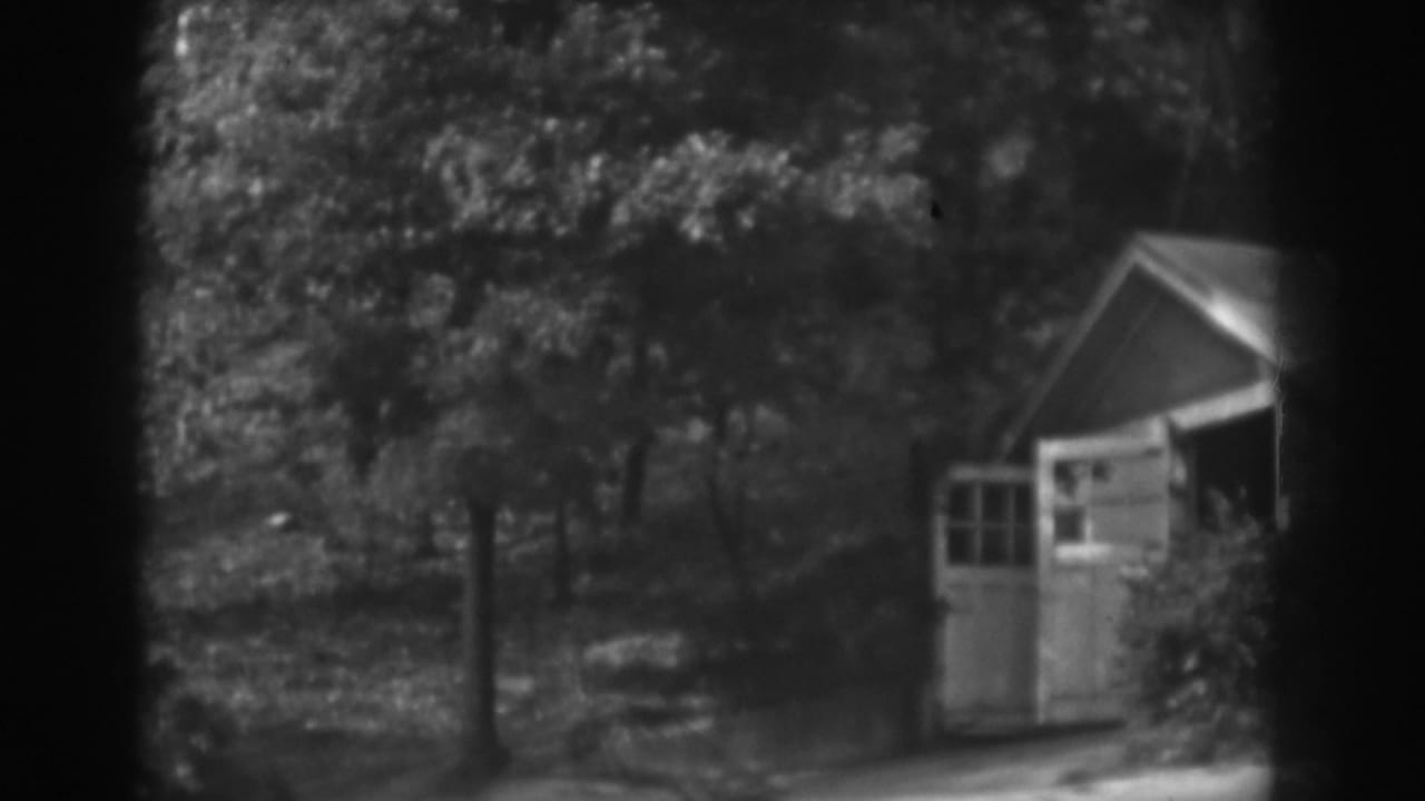 1938 Vineland, New Jersey home-movie frame showing a small shed with open doors on a tree-covered hillside.